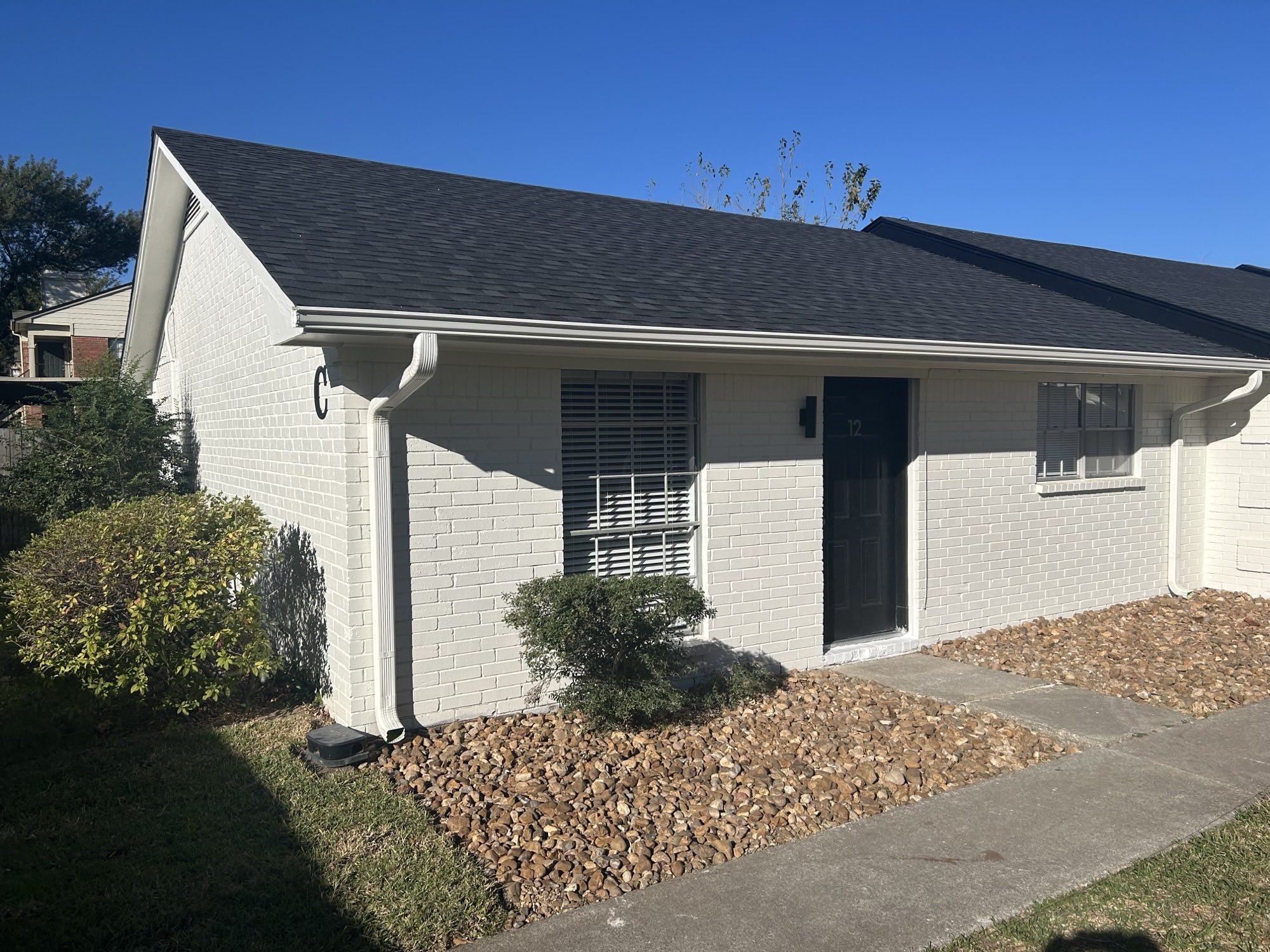 Luna Bay Townhomes exterior — white brick townhome with private entrance, new roof, and landscaped rock beds